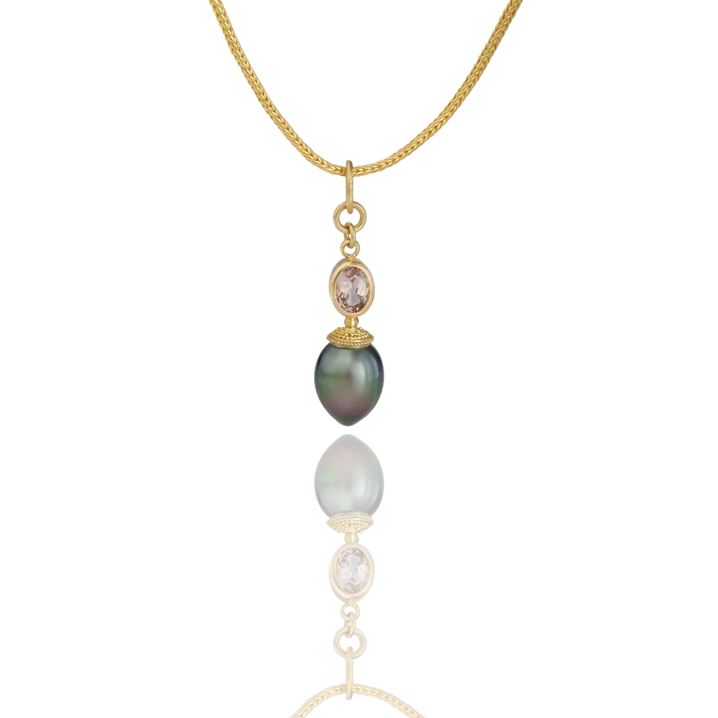 A collectors charm! An iridescent pearl whose color moves from deep green through bronze, is paired with tanzanite - a stone normally associated with blues and violet blues. The buttery tones of high karat gold in the granulated cap give texture and warmth to the gem and pearl, making this a collector's piece indeed. Length approx. 39mm, width 10.3mm (L 1.5in W .4in). Made from recycled 22k gold, a 13.7x10.3mm cultured Tahitian pearl and D Block natural tanzanite (.88ct). Chain is available separately.