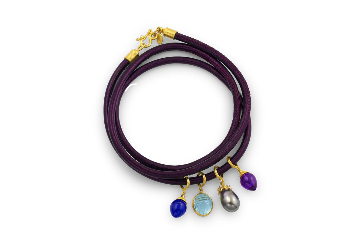 Eggplant Tahitian pearl charm shown on a aubergine colored leather bracelet with other charms.