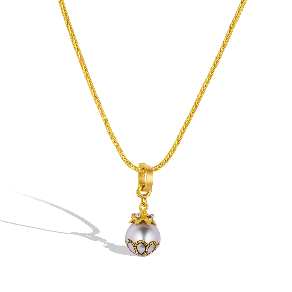 The Maki-e pearl with Anthill garnets charm shown on a handwoven gold chain.