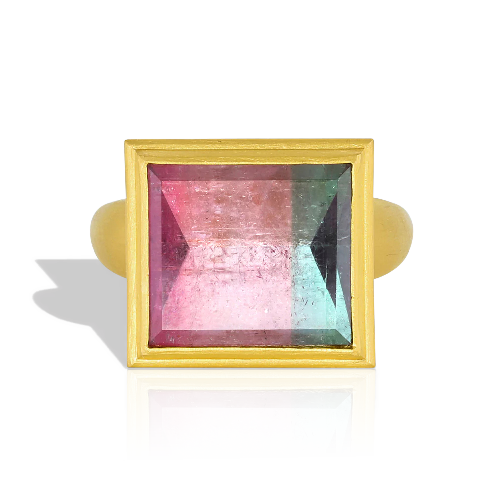 One of our custom cut bi-color tourmalines, this beautiful rectangular lozenge shape gem is a vibrant pink and blue with a glittering, reflective surface. This particular cut gives a mirror like polish to the gem (hence the name "mirror cut"), whereby you can see the intricate open latticework on the high bezel setting is reflected in it. 

Made from recycled gold and a tourmaline (10.29ctw) from Itambacurí, Brazil. Size 7. Can be resized. One-of-a-kind.
