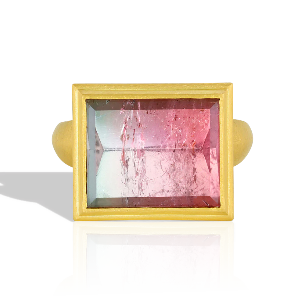 This beautiful rectangular lozenge shape tourmaline (9.42ct) is an unusual metallic salmon pink and teal with a glittering, reflective surface. Mirror cutting a gem does exactly that - gives a mirror like polish to the gem (hence the name), reflecting the intricate open latticework on the high bezel setting. 

Made from recycled 22k gold and a bi-color tourmaline from Itambacurí, Brazil. Size 7. Can be resized. One-of-a-kind.
