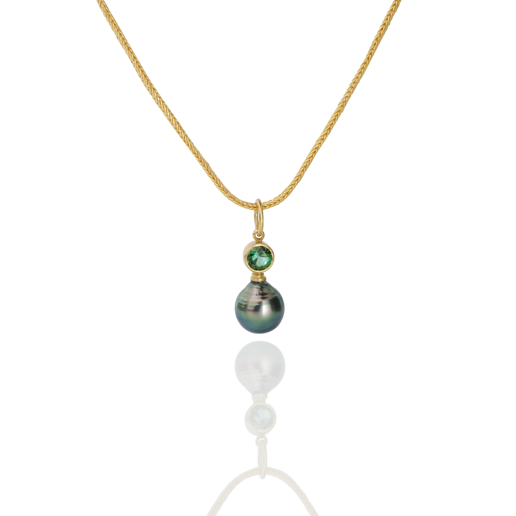 The Green charm shown on a handwoven gold chain.