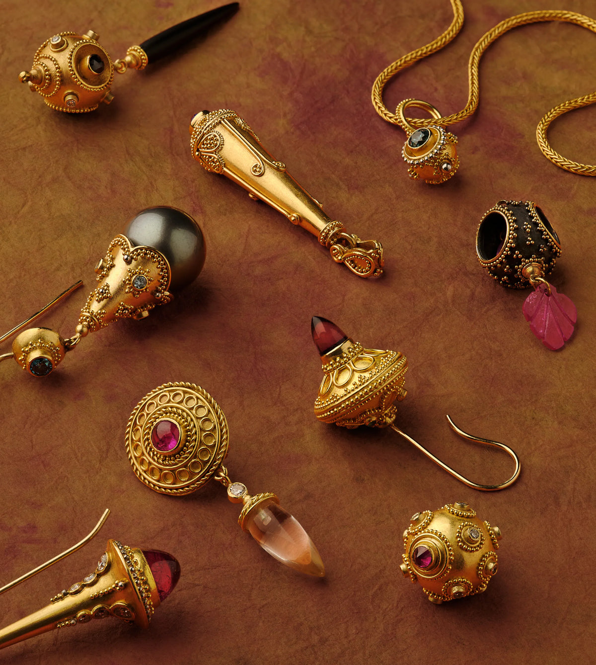 Assorted hand-raised hollow gold pendant and earring drops set with garnet, sapphire, and tourmaline, some finished in oxidized black